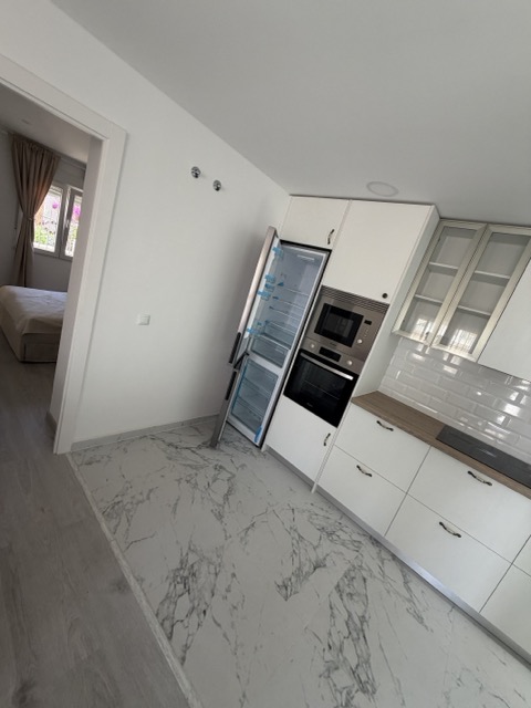 Modern white kitchen with marble flooring and integrated appliances